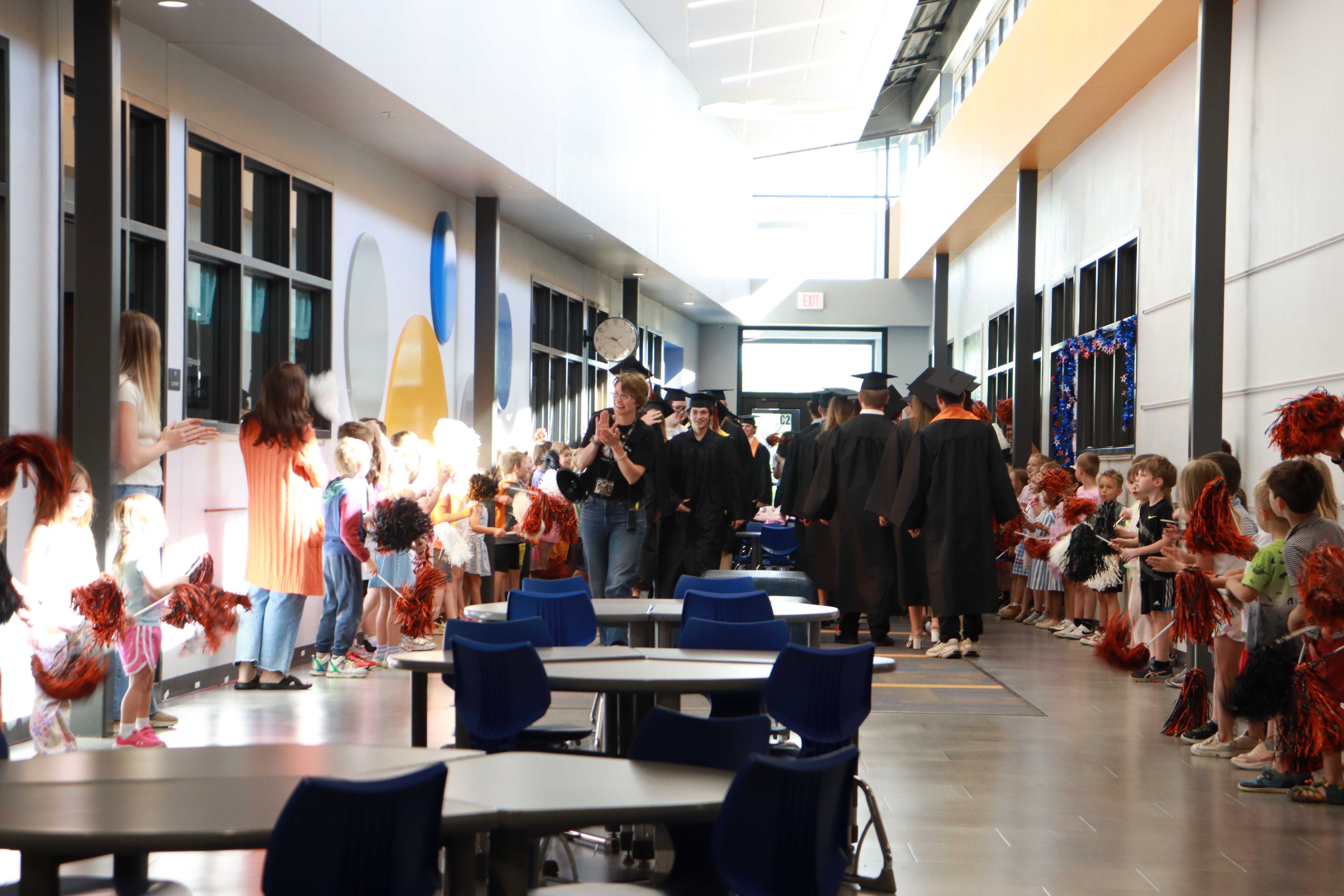 Graduate students walking the halls and being congratulated by future graduates.